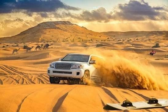 A 4x4 driving over red sand dunes on a desert safari near Dubai